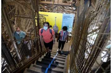 People wearing protective face masks climb the stairs as they visit the Eiffel Tower in Paris on its reopening day to the public following the coronavirus disease (COVID-19) outbreak 